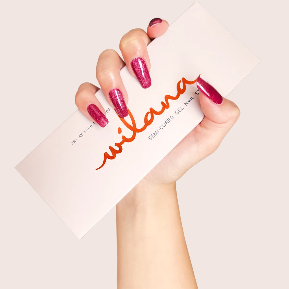 Hand with pink nail polish holding a Wilava product box on a light background
